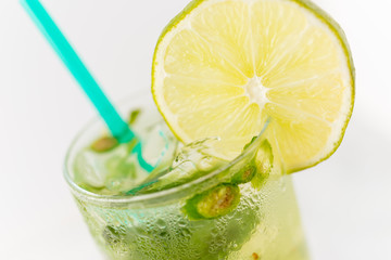Spice jalapeño margarita with lime wedge over ice in glass with green straw