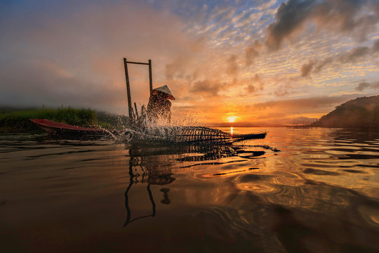 Fisherman fishing in river during sunset