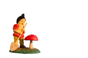 Close-up of miniature vintage gardening gnome with a small shovel and red poison toadstool, mushroom