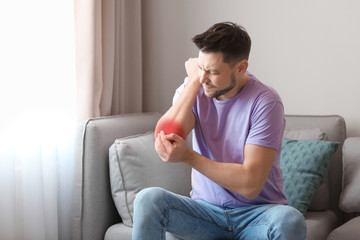Young man suffering from elbow pain at home