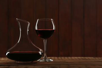 Elegant decanter and glass with red wine on table against dark background