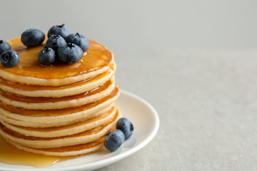 Plate with pancakes and berries on grey background, closeup