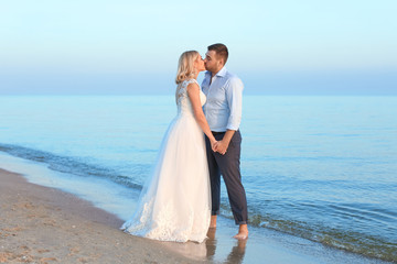 Fototapeta na wymiar Wedding couple. Groom kissing bride on beach