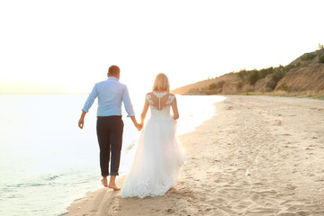 Fototapeta na wymiar Wedding couple holding hands together on beach. Space for text