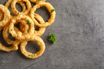 Homemade crunchy fried onion rings on color table, top view. Space for text