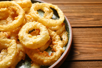 Homemade crunchy fried onion rings on wooden table, closeup