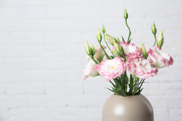 Fototapeta na wymiar Beautiful flowers in vase and space for text on blurred background. Element of interior design