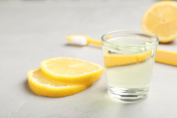 Glass with mouthwash and lemon on light background. Teeth care