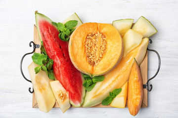 Flat lay composition with tasty sliced melons and watermelon on white wooden background