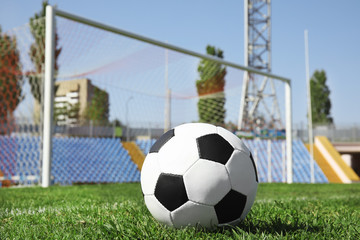 Soccer ball on green football field grass against net