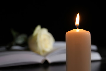 Burning candle on blurred background, space for text. Funeral symbol