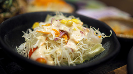 Lettuce salad in a black bowl.