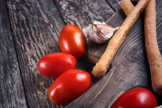 grissini, tomatoes and garlic on the wooden cut board