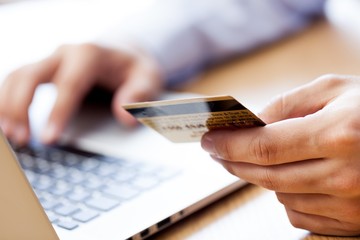 Closeup of a Man Typing on a Laptop and Holding a Credit Card - obrazy, fototapety, plakaty