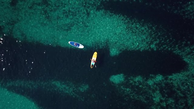 Video from above, aerial view of  two people on a stand up paddle (SUP) in Sardinia, Italy.