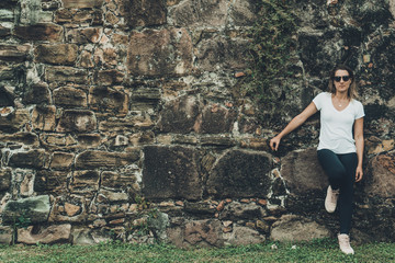 Young blonde leaning on a stone wall