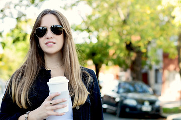 Woman holding paper coffee cup in the street.