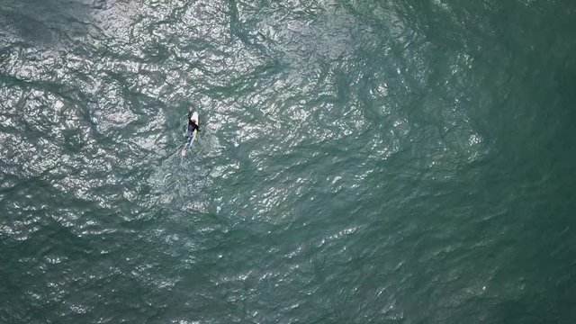 Drone shot of a Surfer from above paddling in the famous Coxos surfspot in Ericeira. HD.