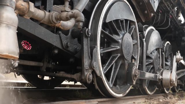 Steam engine locomotive venting and dripping water while at railway station