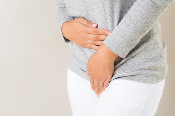 Young woman having painful stomachache with hands holding pressing her crotch lower abdomen. Medical or gynecological problems, healthcare concept