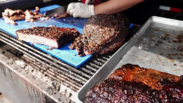 BBQ grill chef carves smoked beef brisket