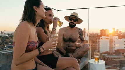 young woman and man people enjoying a beer and the company at a rooftop bar above the city with beautiful view with a cute pet dog