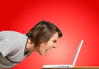 Furious young man screaming on laptop