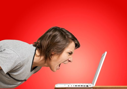 Furious young man screaming on laptop
