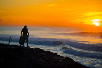 Fototapeta premium An Indonesian Man collecting garbages nearby the ocean of the Bali island, Indonesia. Bali is known as the beautiful ocean view with with exotic culture of Indonesia.