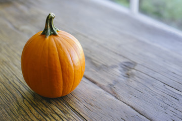 Small Sugar Pumpkin atop a wooden farm table