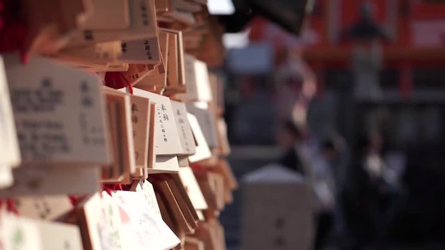 Ema with handwritten prayers hanging from a wall at a Shinto shrine temple in Kyoto, Japan.