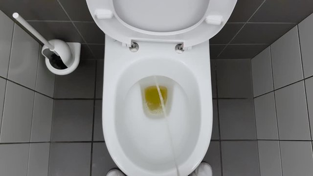 Top down view of Man urinating into white toilet bowl