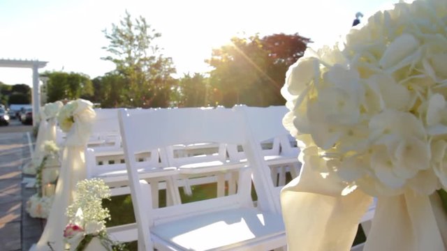 White chairs set in rows with white bows and flowers
