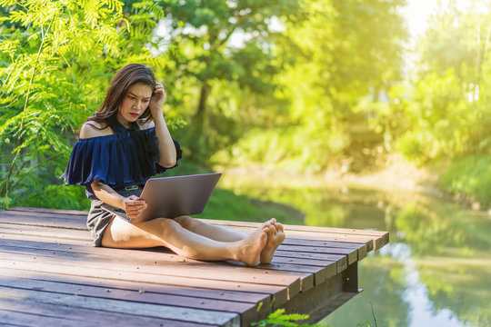 Stressed Woman Using Laptop Computer On Wooden Jetty