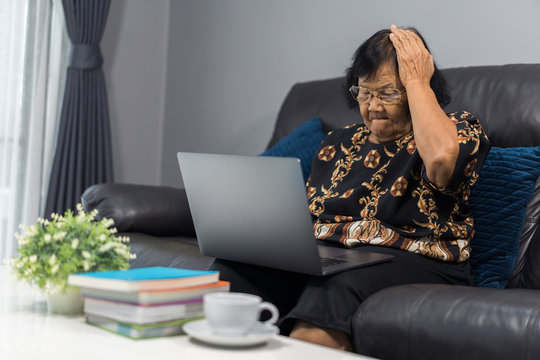 stressed senior woman working on laptop in living room