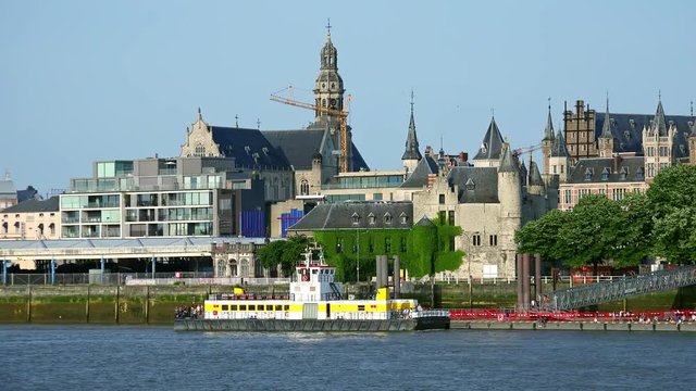 ANTWERP, BELGIUM - MAY 26, 2018: Pleasure boat with tourists sailing along Scheldt river during sightseeing tour and mooring to berth against St. Paul's Church and Het Steen castle on background.