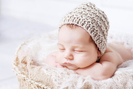 Sweet newborn baby sleeps with a toy in the basket. Newborn boy folded handles  in a basket. Close up image. White background.