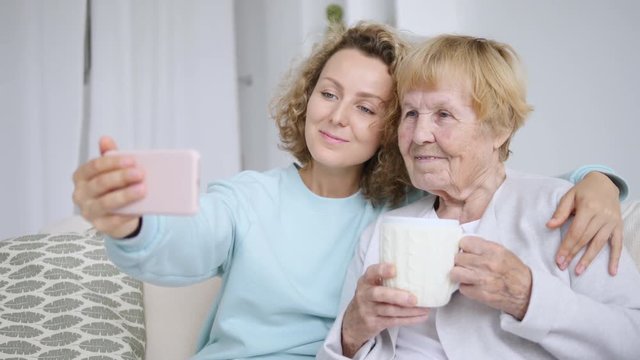 Close-Up Portrait Of Joyful Happy Elderly Grandmother Taking Selfie With Granddaughter
