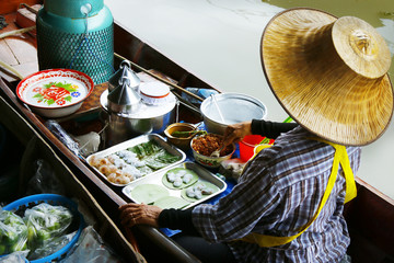 Woman trading fruit and food in boats at Damnoen Saduak floating market ,Thailand