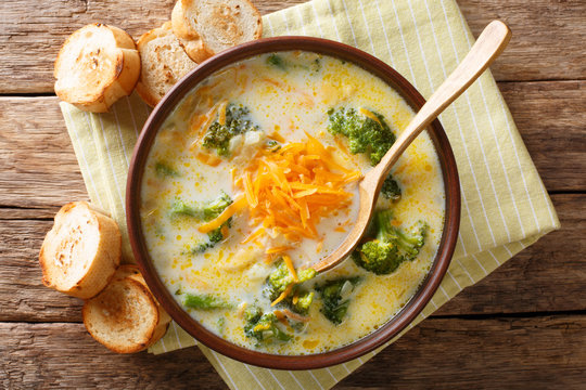 Delicious cheesy broccoli soup with vegetables in a bowl with toast close-up. horizontal top view