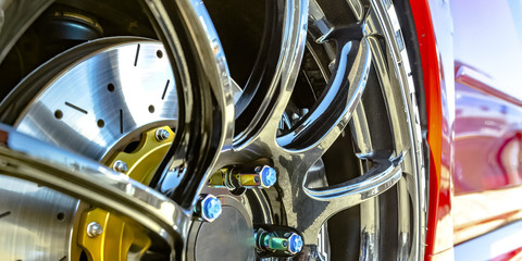 Polished mag wheel with blue bolt caps of a car