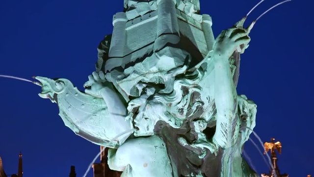 Close-up of bronze decorations of Brabo Fountain depicting scene from Flemish legend. Beautiful details of popular historical landmark illuminated at evening. Great Market Square, Antwerp, Belgium.