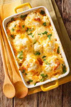 Delicious baked fresh cauliflower with cheese sauce close-up in a baking dish. Vertical top view