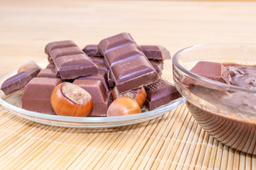 Chocolate slices and hot melted chocolate. Chocolate with hazelnuts. Nuts of hazelnuts.