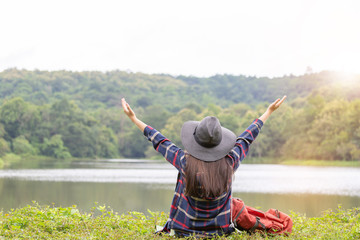 Young traveler woman with black hat in hipster style sitting relax at lake blurred background