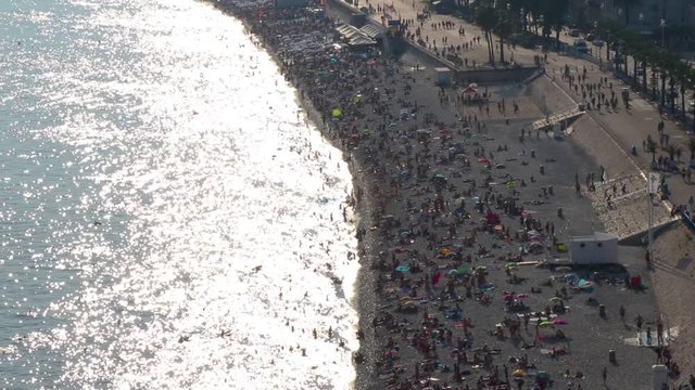 Crowded beach and Promenade des Anglais in Nice, southern France, seen from above (bird's eye). Scene of the 2016 terrorist attack. Establishing shot.