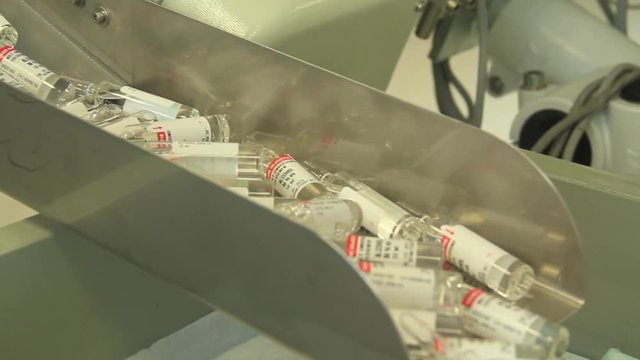 Large batch of medicinal vials being transported from machine.