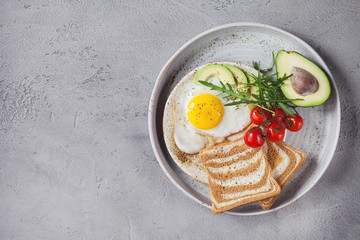 breakfast with fried egg with avocado, tomatoes and bread