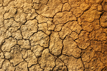 Dry cracked orange stony soil, top view.
