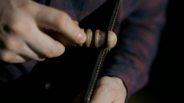 The process of manufacturing a leather wallet handmade. The craftsman grinds the finished product. Handmade leather goods. Slow motion.